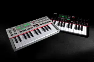 Two compact MIDI keyboard controllers with white and black keys and control pads rest on a black leather surface—perfect gift ideas for musicians who value portability and versatility in their setup.